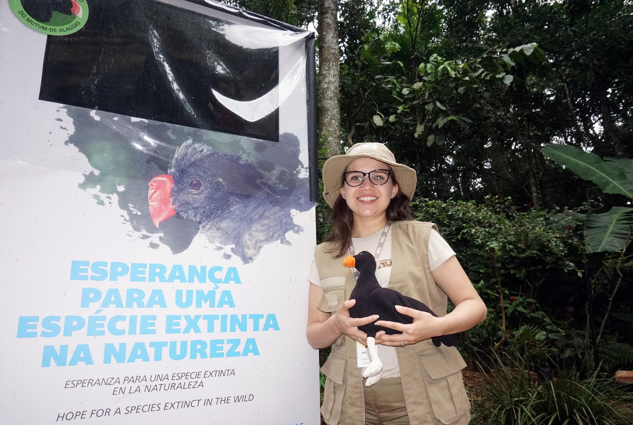 Mulher segurando uma pelúcia em frente a uma placa