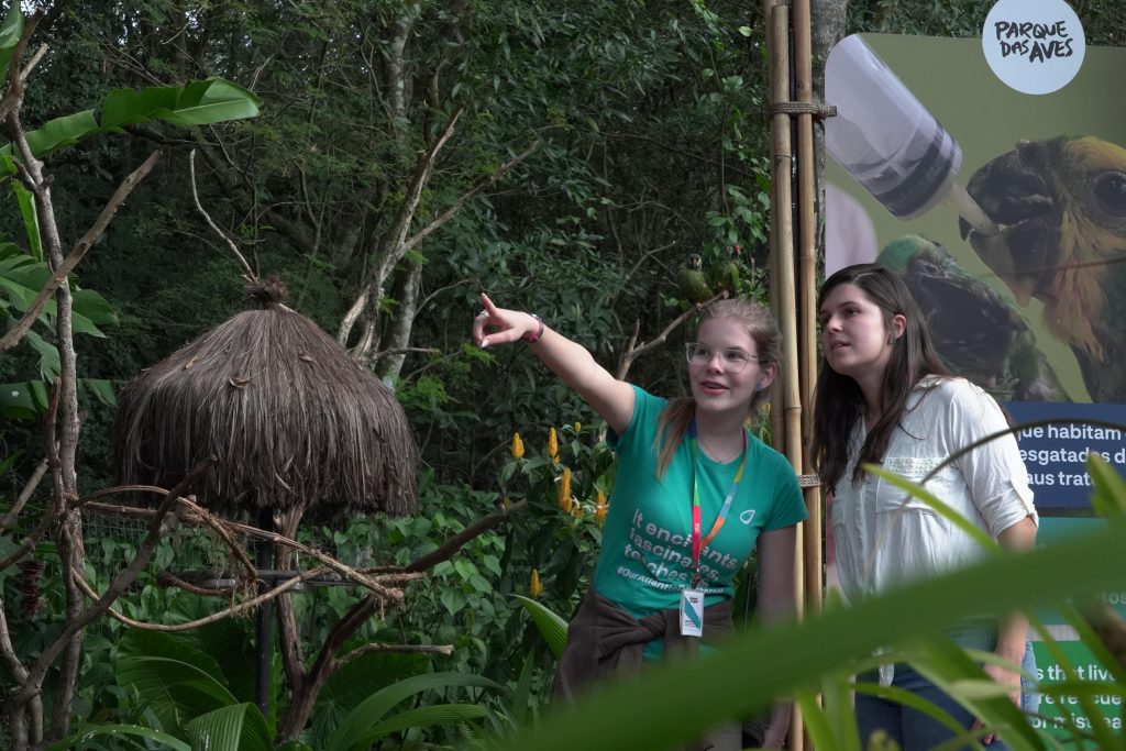 Uma mediadora de trilha auxilia uma visitante na trilha