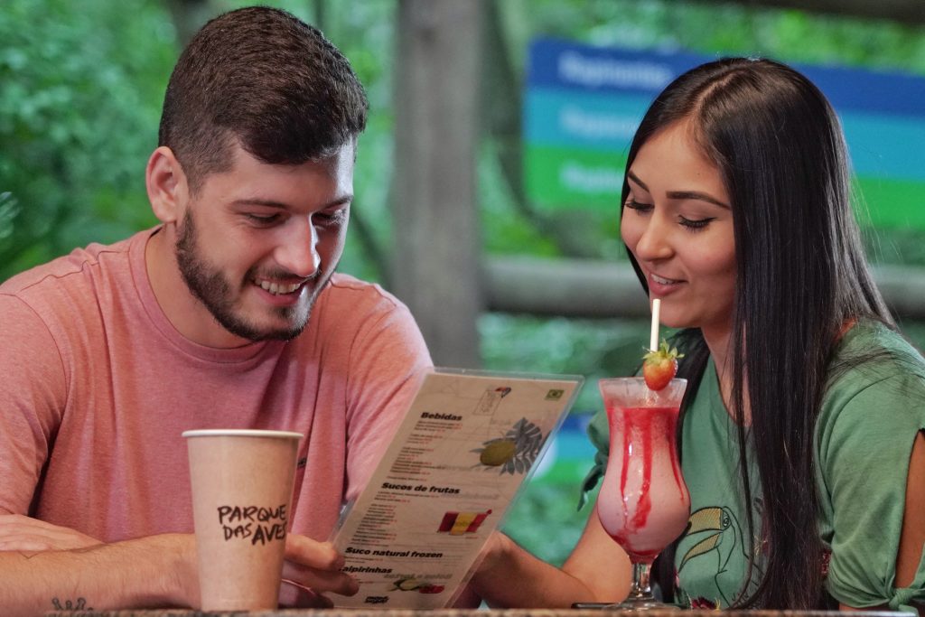Foto de um casal escolhendo um pedido no cardápio