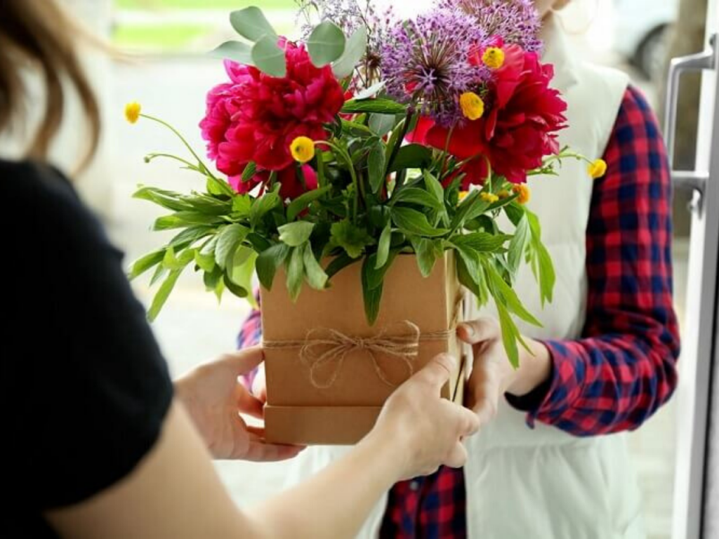 Uma mulher entregando um vaso com flores para outra mulher