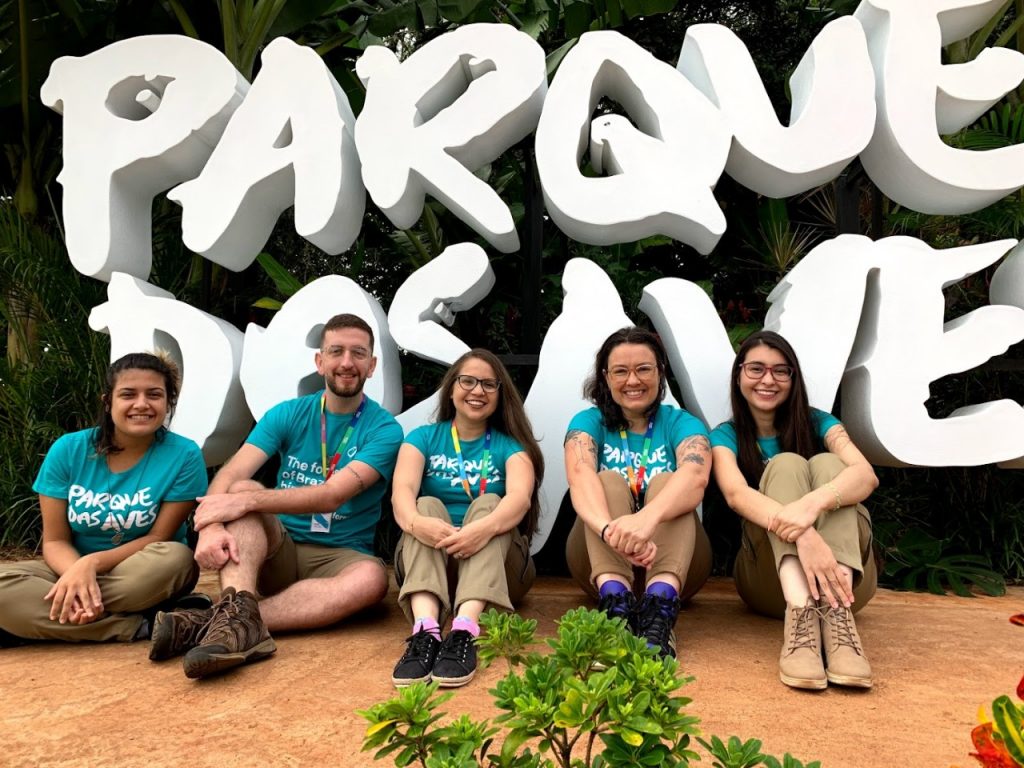 equipe-de-comunicação-em-frente-à-placa-do-parque-das-aves