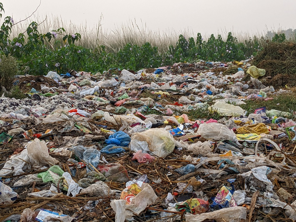 Montanha de lixo plástico acumulado em área de vegetação, mostrando o impacto do descarte inadequado no meio ambiente. planeta