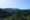 Vista panorâmica da Mata Atlântica com vegetação densa e montanhas ao fundo sob céu azul claro.