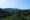 Vista panorâmica da Mata Atlântica com montanhas cobertas por densa vegetação verde sob um céu azul claro.