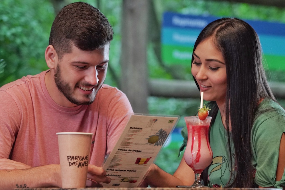 Casal com cardápio em mãos fazendo seu pedido.