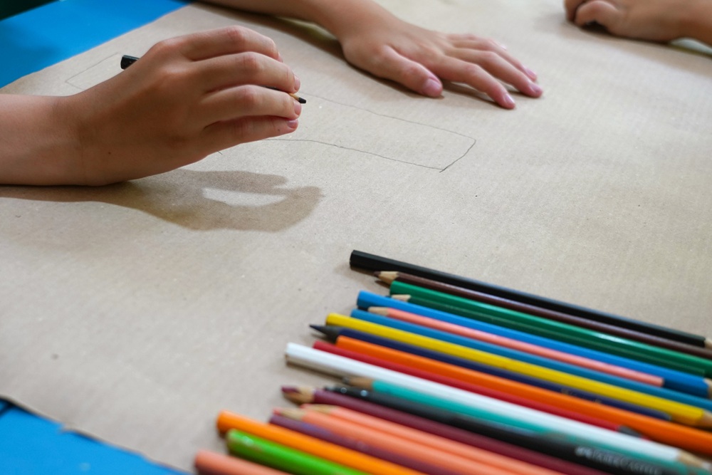 Criança desenha com lápis de cor para o concurso da Mata Atlântica.
