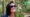 Papagaio sobre tronco em primeiro plano, com visitante sorrindo ao fundo e selo do Tripadvisor 2025 indicando premiação ao Parque das Aves.