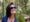 Mulher sorrindo ao lado de um papagaio em um dos viveiros do Parque das Aves.