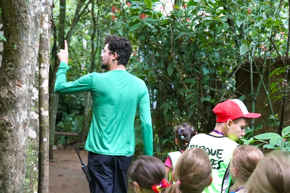 Monitor do Parque das Aves orienta grupo de crianças durante trilha na Mata Atlântica.