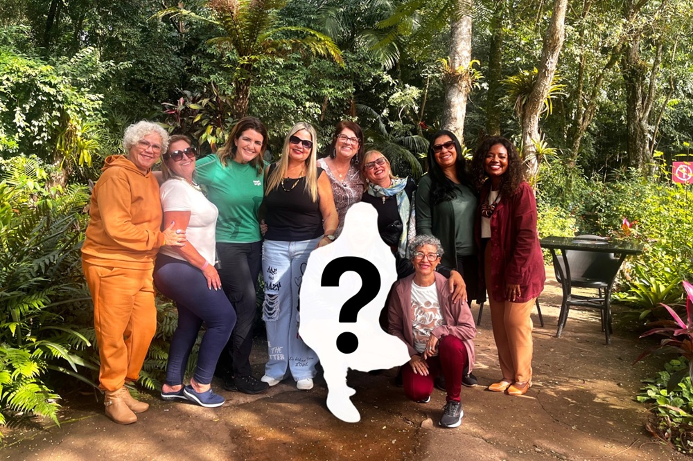 Grupo de mulheres posa para foto no Parque das Aves com silhueta de um participante ainda não revelado no centro da imagem.