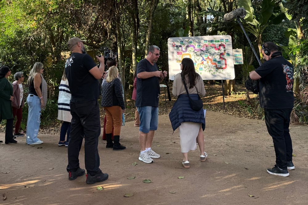 Equipe de gravação registra a movimentação no início do percurso do Parque das Aves, próximo ao mapa do atrativo.