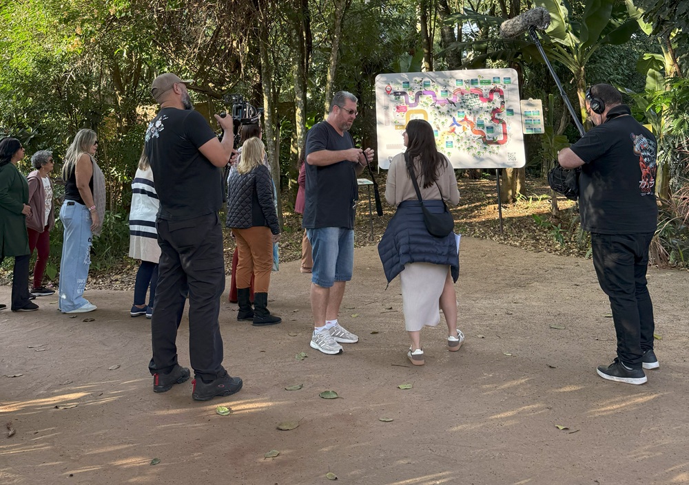 Equipe de gravação do programa Caldeirão com Mion entrevista visitantes em frente ao mapa do Parque das Aves.