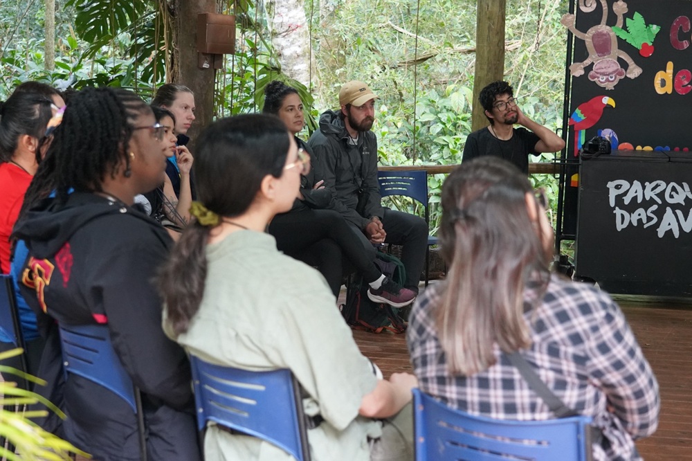 Grupo internacional acompanha palestra no auditório ao ar livre do Parque das Aves, durante programação especial.