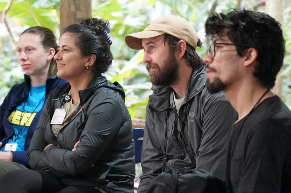 Participantes internacionais atentos durante roda de conversa no Parque das Aves, cercados pela vegetação da Mata Atlântica.